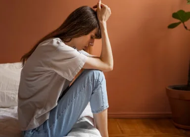 женщина с депрессией сидит на кровати